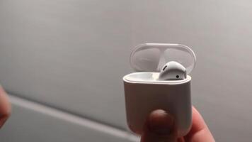 Man's hand puts airpods in a box. Concept. Man puts the airpods headphones in the box for charging video