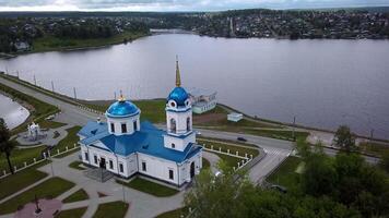 panorama- antenn se av kloster på en sommar dag. klämma. skön vit kyrka med blå tak nära damm. video