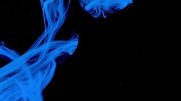Blue ink drops underwater on a black background. Stock footage. Close up of beautiful blue paint flowing underwater. video