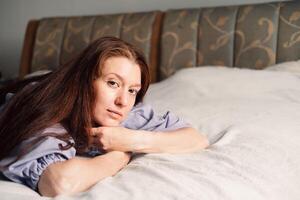 como Mañana ligero filtros en, un mujer mentiras en sereno contemplación, abrazando el quietud de dormitorio foto