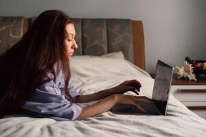 temprano rayos de ligero ojeada mediante como un mujer empieza su día trabajando desde su cama foto