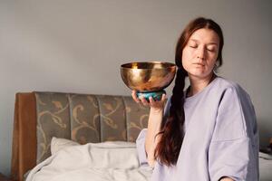Engrossed in meditation, a woman with a singing bowl exemplifies a serene state photo