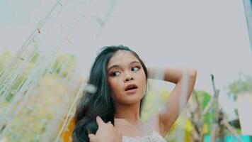 Low-angle view of a young woman outdoors, with a dreamy expression and soft focus background. video