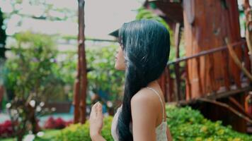 Rear view of a woman with black hair enjoying a tranquil garden setting. video