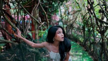 Side view of a woman exploring a lush green forest with hanging vines. video