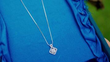 fermer de une argent cœur pendentif sur une Collier contre une bleu en tissu Contexte. video