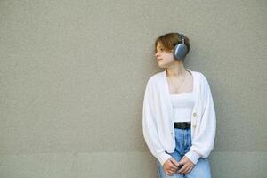 retrato de un Adolescente niña en auriculares en contra un gris pared. foto