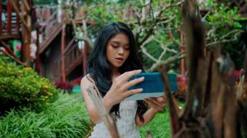 Jeune femme en utilisant tablette dans une luxuriant jardin paramètre. video