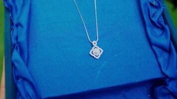 Elegant silver necklace with a rose pendant on a blue satin background. video