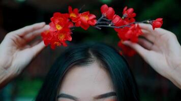 Close-up of a woman holding vibrant red flowers above her head, with focus on the flowers and blurred background. video
