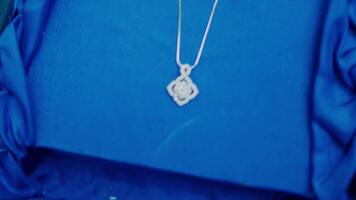 Close-up of a person's hands holding a blue velvet box with an elegant pendant necklace inside. video