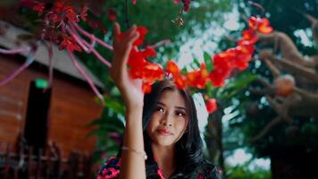 Serene woman touching vibrant red flowers, with a soft-focus background. video