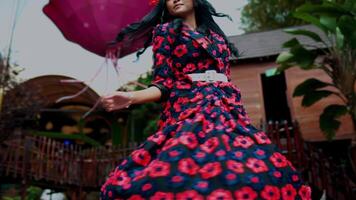 floue Jeune fille dans une floral robe en jouant dans une jardin avec une capricieux atmosphère. video