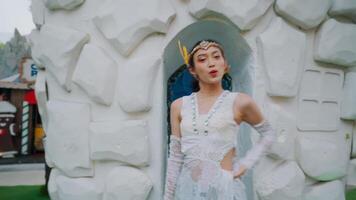 Woman in a white dress posing at a whimsical ice castle entrance. video