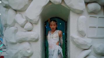 Woman in a white dress posing at a whimsical ice castle entrance. video