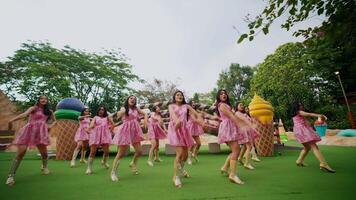 flou mouvement de une groupe de danseurs dans rose Robes performant en plein air, convoyer énergie et mouvement. video