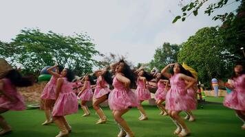 groep van blij kinderen dansen buitenshuis in roze jurken, uitdrukken geluk en viering in een park instelling. video