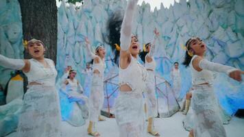 Blurred image of people in white costumes dancing, with a whimsical winter backdrop and penguin figures. video