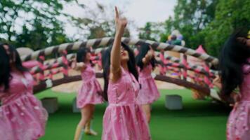 Group of girls in pink dresses dancing outdoors with a whimsical backdrop. video