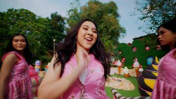 Group of joyful women in pink dresses celebrating outdoors with a focus on a smiling woman in the foreground. video