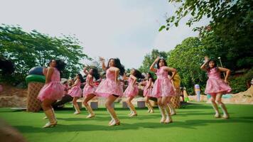 grupo de niños en rosado vestidos bailando al aire libre en un soleado día. video