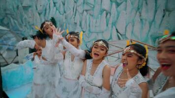 wazig beweging van vier blij dansers in wit kostuums met hoofddeksels, het uitvoeren van met expressief gebaren. video