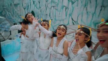 Blurred motion of four joyful dancers in white costumes with headpieces, performing with expressive gestures. video