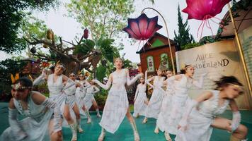 grupo de intérpretes en blanco disfraces bailando a un al aire libre evento con vibrante decoraciones en el antecedentes. video