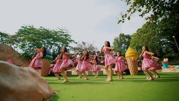 grupo de niños en rosado vestidos alegremente bailando al aire libre en un soleado día, expresando libertad y felicidad. video