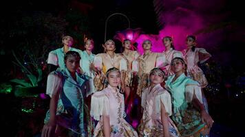 grupo do artistas dentro vintage fantasias posando debaixo colorida etapa luzes às noite. video