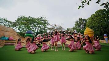 Group of girls in pink dresses dancing outdoors with a whimsical backdrop. video