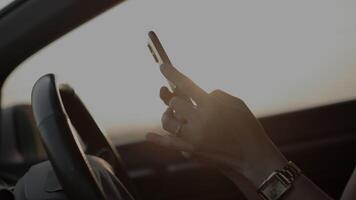 Hand using phone in car at sunset in summer, travel concept video