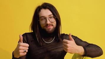 Young smiling happy cheerrful bisexual man in glasses and mesh t-shirt isolated on yellow color background video