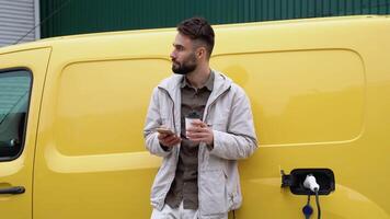 ein Spanisch Mann Getränke Kaffee während Laden ein elektrisch Wagen. Grün Energie, Öko freundlich Treibstoff video