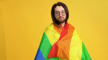 Mens Holding regenboog vlag lgbt Aan geel achtergrond. homo trots concept. stemmen voor homoseksueel liefde video