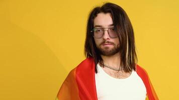 Man bisexual holding rainbow flag LGBT on yellow background. Gay pride concept. Vote for homosexual love video