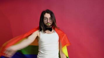 joven activista sonriente contento gay hombre sostener arco iris bandera aislado en rojo antecedentes estudio. personas lgbt estilo de vida concepto video