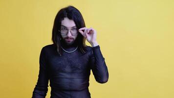 Young smiling happy cheerrful gay man in glasses and mesh t-shirt isolated on yellow color background. Lifestyle lgbtq pride concept video