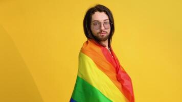 Man holding rainbow flag LGBT on yellow background. Gay pride concept. Vote for homosexual love video