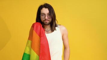 Man bisexual holding rainbow flag LGBT on yellow background. Gay pride concept. Vote for homosexual love video