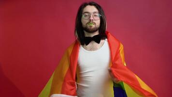 Young activist smiling happy transgender man hold rainbow flag isolated on red background studio. People lgbt lifestyle concept video
