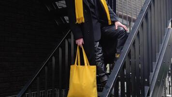 Young caucasian stylish man outside wearing coat and yellow scarf after shopping with yellow bag video