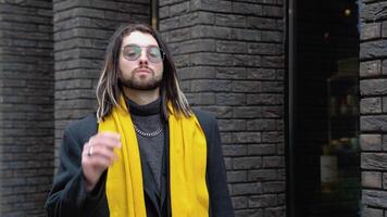 Portrait of a young caucasian stylish man outside in a coat and yellow scarf video