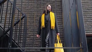 Young caucasian stylish metrosexual man outside wearing coat and yellow scarf after shopping with yellow bag video