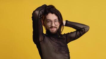 Young smiling happy cheerrful bisexual man in glasses and mesh t-shirt isolated on yellow color background. Theme of equality and freedom of choice video