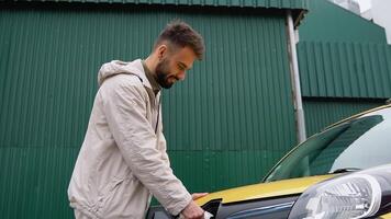 Happy man charges an electric car at a charging station. Electric car charging video