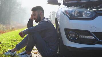 triste chauffeur est assis près une cassé voiture dans le milieu de le Autoroute video