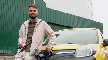 une homme avec une chargeur à une mise en charge station regards dans le caméra video