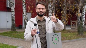 A bearded turkish man with a charger at a charging station looks into the camera video