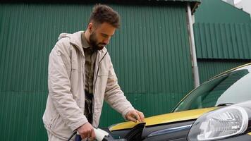 Happy man charges an electric car at a charging station. Electric car charging. Electric car charging concept video